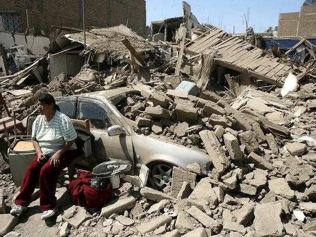 Una mujer sentada en la fachada de su casa derrumbada durante el terremoto de Pisco de 2007. (Foto: AFP)